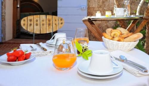 Petit-déjeuner à la Villa Marina Di Cavu avec fraises fraîches, jus d'orange, corbeille de pain et couverts avec vue panoramique