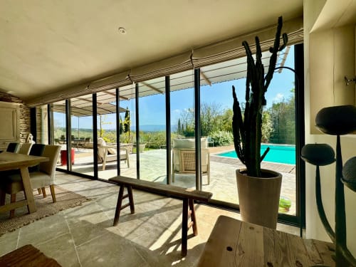 Interieur van B&B Provence Km28 in Gordes met zwembadview, zwarte cactusplant, moderne ramen en Mediterraan landschap