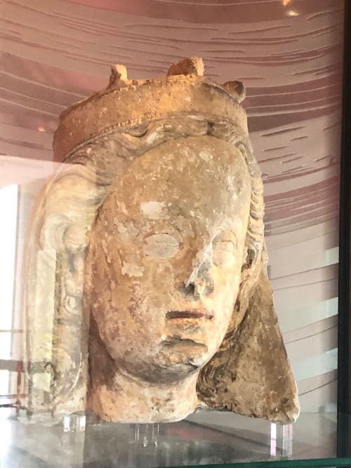 Ancient stone head sculpture displayed at Domaine de l'Ocrerie in Pourrain, France