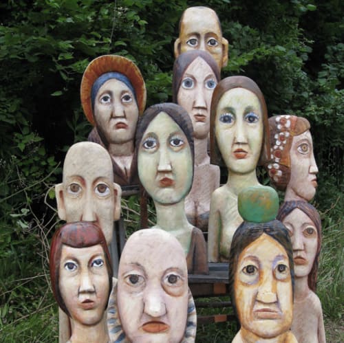 Carved wooden head sculptures displayed in garden at Domaine de l'Ocrerie, Pourrain
