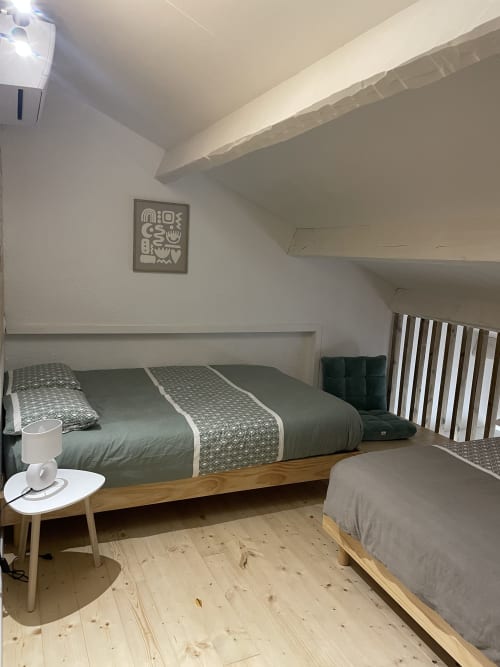 Chambre cosy de la villa Mazet Cavalaire à Cavalaire-sur-Mer avec lit en bois, literie verte et puits de lumière