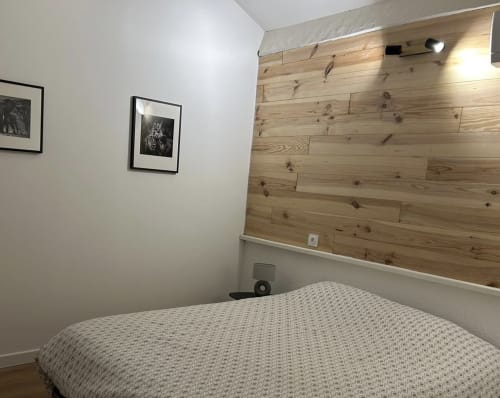 Chambre moderne de la villa Mazet Cavalaire avec tête de lit en bois, murs blancs, tableaux encadrés et vue mer à Cavalaire-sur-Mer