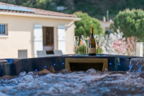 Verres et bouteille de vin sur le rebord du bain à remous de la Maison Love Lane, Cagnes-sur-Mer, avec villa méditerranéenne en arrière-plan