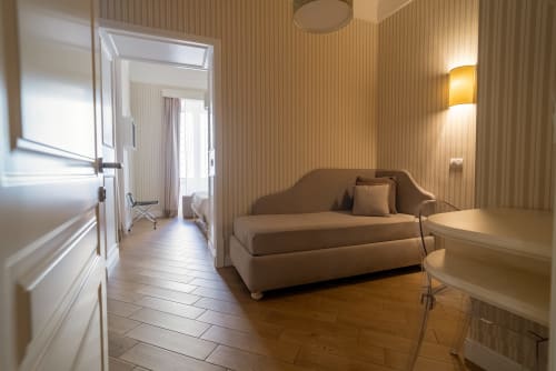 Suite Florita Triple Comfort di Le Boutique del Centro Napoli - moderna con divano beige, scrivania e vista sulla città
