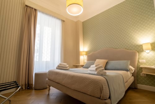 Camera tripla Florita Napoli al Le Boutique del Centro con letto beige, carta da parati decorata, pavimenti in legno e vista città