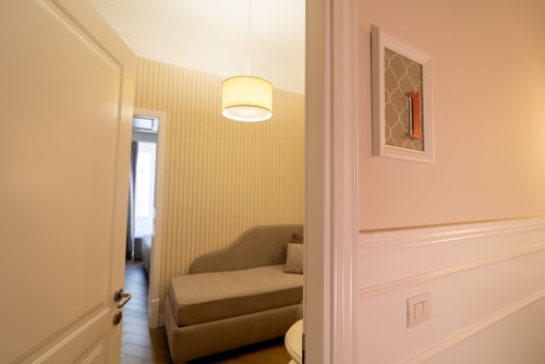 Camera d'hotel moderna presso Le Boutique del Centro a Napoli con comoda zona living, carta da parati gialla e plafoniera