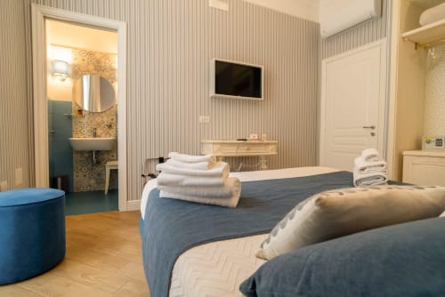 Camera matrimoniale moderna presso Le Boutique del Centro a Napoli con letti blu, carta da parati a righe, bagno en-suite e