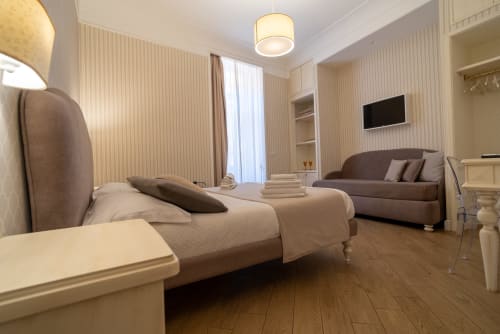 Elegante camera tripla executive a Le Boutique del Centro a Napoli con letto queen, zona salotto e vista sulla città