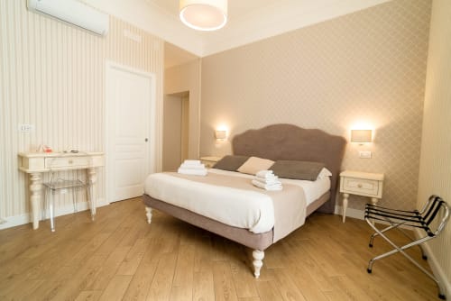 Camera elegante al Le Boutique del Centro di Napoli con letto matrimoniale, parquet, carta da parati beige decorata