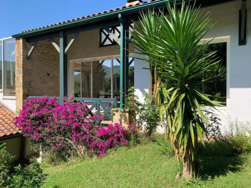 Terrasse de la Chambre Amazonie de Villa Ongizatea avec bougainvillée magenta éclatante, palmier et vues montagneuses à Urrugne