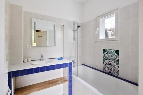 Modern bathroom with blue tile accents, white sink, mirror, shower, and window at Villa Ongizatea cottage in Urrugne