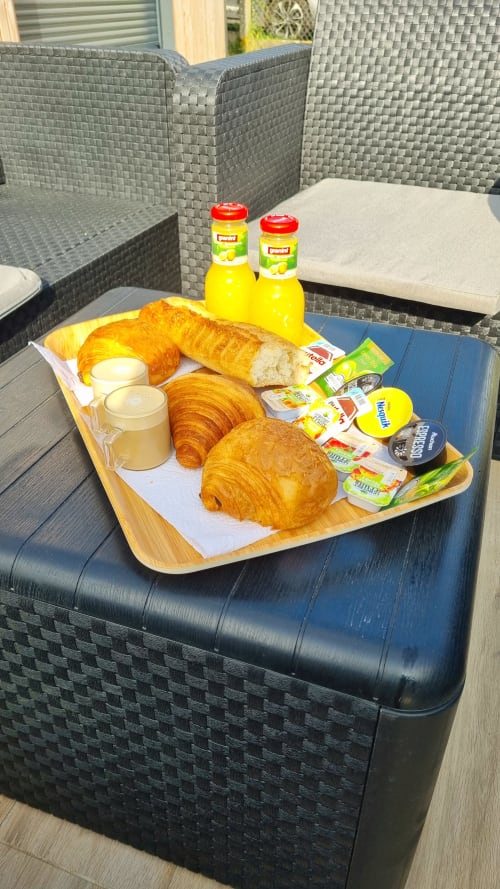 Continental breakfast tray at Ilot Cosy and Spa featuring croissants, butter, jam, fresh bread and orange juice on patio