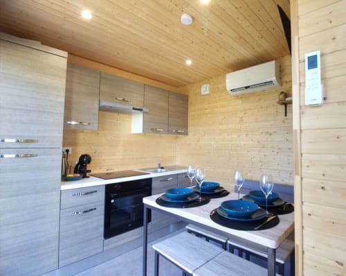 Modern kitchen and dining area in wooden cabin at Ilot Cosy and Spa, Luçay-le-Mâle with place settings