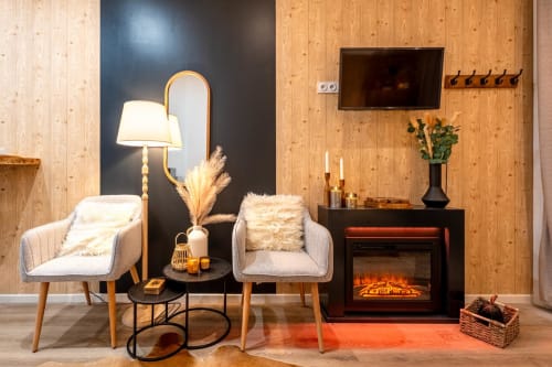 Cozy living room in Wellkhome Bordeaux with fireplace, two armchairs, lamp, and wood-paneled walls