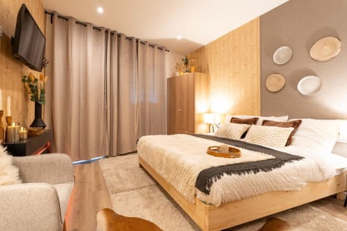 Wellkhome Le Nid Douillet apartment bedroom in Bordeaux with wooden bed, cork walls, flat-screen TV, and modern furnishings