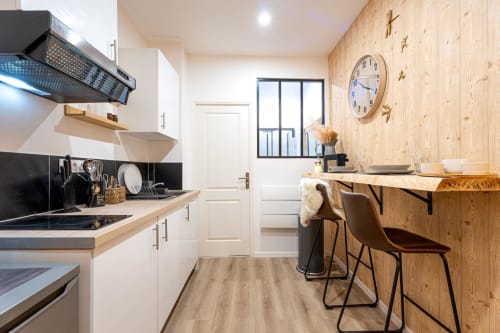 Modern kitchen-dining area in Wellkhome Bordeaux apartment with wooden accents, white cabinetry, and city view