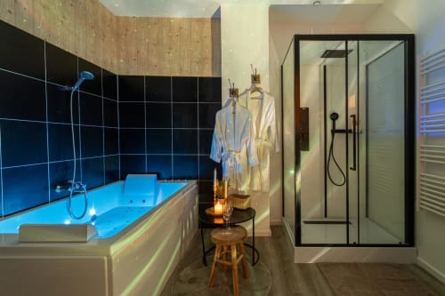 Luxurious Bordeaux apartment bathroom with illuminated jacuzzi tub, rainfall shower, and spa amenities at Wellkhome