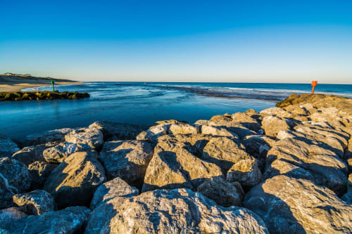 Plage rocheuse de Mimizan avec eaux turquoise et rochers dorés aux Logis d'Argent