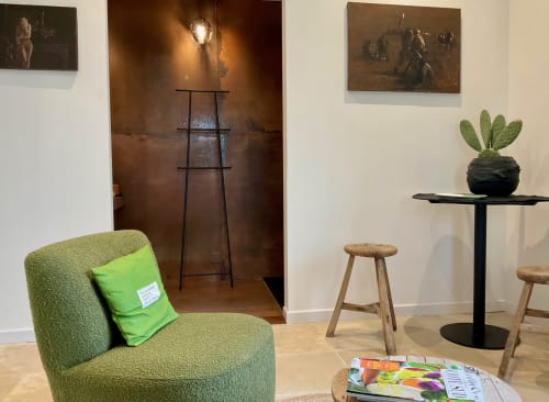 Modern lounge area in Les Oliviers room at Provence Km28 with green chair, potted cactus, and art pieces