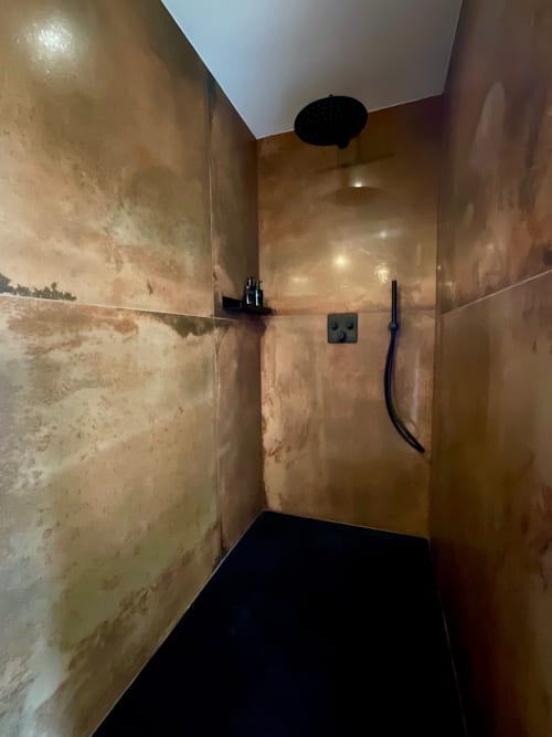 Modern shower enclosure with beige tile walls and black fixtures at Provence Km28 BnB in Gordes