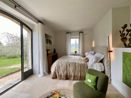 Spacious bedroom with garden view at Provence Km28 in Gordes, featuring bed, green chair, terrace access, and mountain views