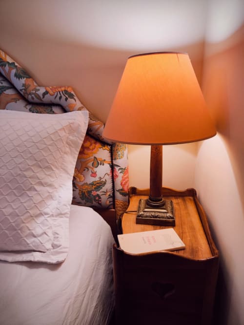 Decorative detail of the Rose guest room at Le Rêve d’Alice with bedside lamp and wooden table