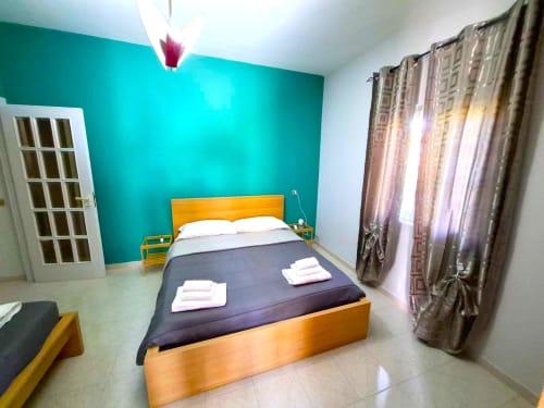 Camera luminosa del Newhouse Bari con parete accent turchese, letto arancione e arredamenti moderni