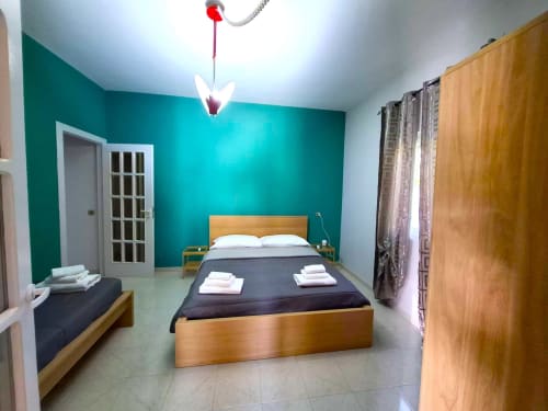 Camera spaziosa dell'hotel Newhouse a Bari con parete turchese, letto in legno e comfort moderni