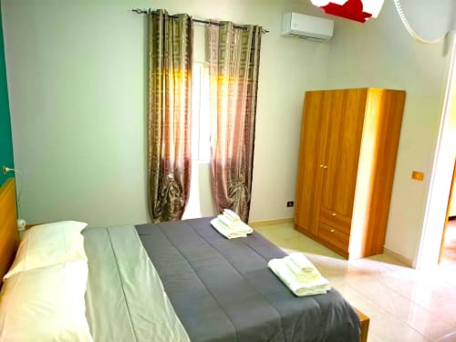 Camera da letto spaziosa dell'appartamento Newhouse Bari con letto matrimoniale, armadio in legno e tende decorate