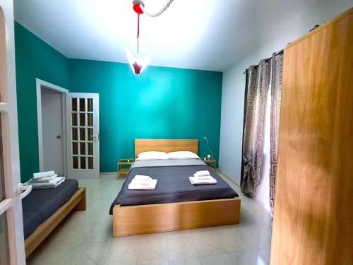 Camera da letto Newhouse a Bari con parete azzurra, letto in legno, comfort moderni e pavimento in piastrelle