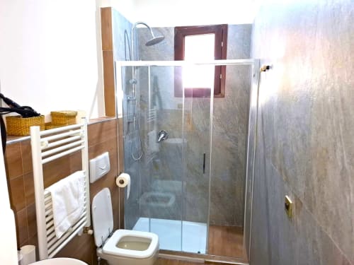 Bagno moderno dell'appartamento Newhouse a Bari con doccia in vetro, toilet, scaldasalviette e rivestimenti in stile marmo