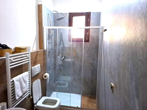 Bagno moderno nell'appartamento Newhouse a Bari con doccia in vetro, scaldarughe bianco, WC e pareti piastrellate