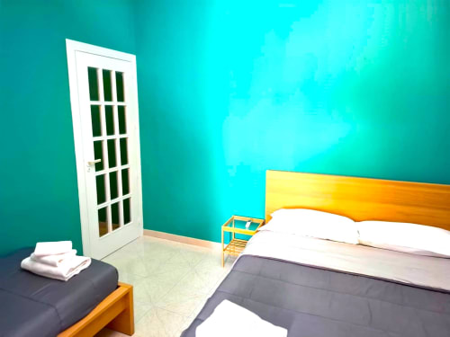 Camera da letto azzurra luminosa presso Newhouse Bari con letto in legno, porta bianca e servizi moderni