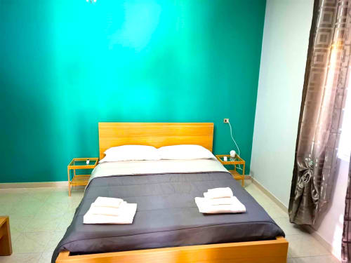 Camera da letto moderna e luminosa a Newhouse Bari con letto in legno giallo, parete accent turchese e biancheria bianca