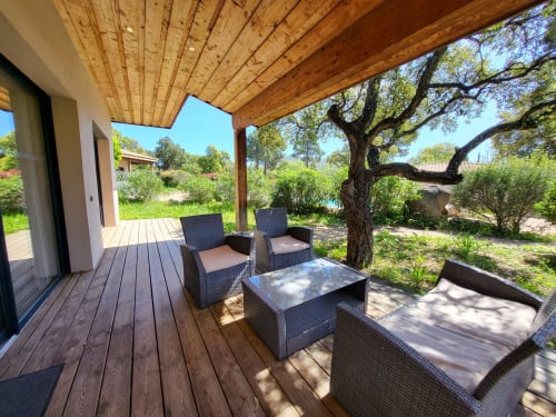 Villas Lantana patio with wooden pergola, rattan seating, and gnarled olive tree in Lecci