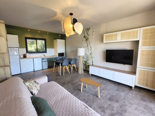 Modern open-plan living area at Villas Lantana Lecci with kitchen, dining table, sofa, and TV unit with natural decor