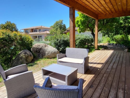 Wooden terrace with rattan seating and coffee table at Villas Lantana, Lecci, overlooking gardens and villa