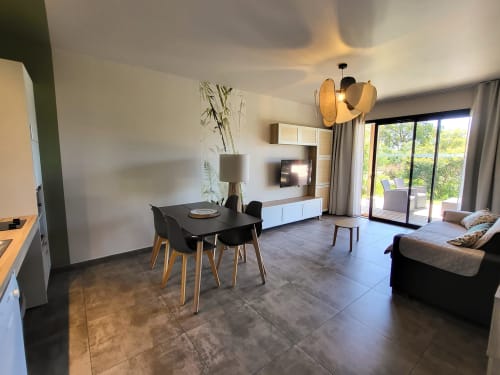 Modern open-plan villa at Villas Lantana in Lecci featuring dining area, living room with TV, and terrace access