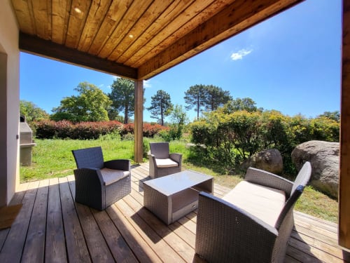 Covered wooden terrace with rattan furniture overlooking lush gardens at Villas Lantana, Lecci