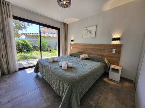 Modern bedroom in 2-bedroom villa at Villas Lantana, Lecci with wooden headboard, patio access, and contemporary furnishings