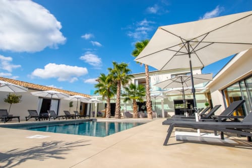 Espace piscine de luxe de La Maison D'ambrine avec transats, parasols et palmiers à Chamaret, France