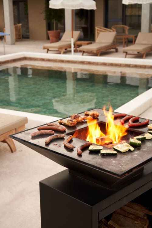 Mesa de fuego al aire libre con carnes y verduras asadas junto a la piscina en La Maison D'ambrine, hotel boutique en Chamaret, Francia