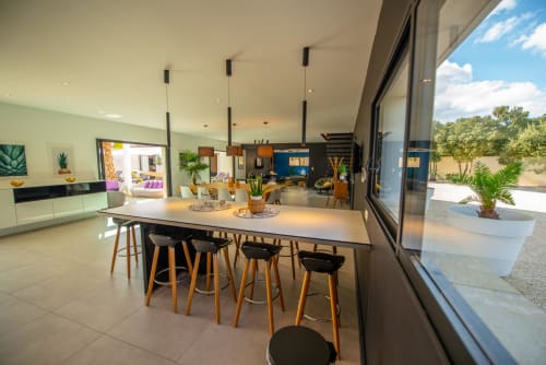 Espace salle à manger moderne de la Villa La Maison D'ambrine avec bar, luminaires suspendus et vue sur la piscine