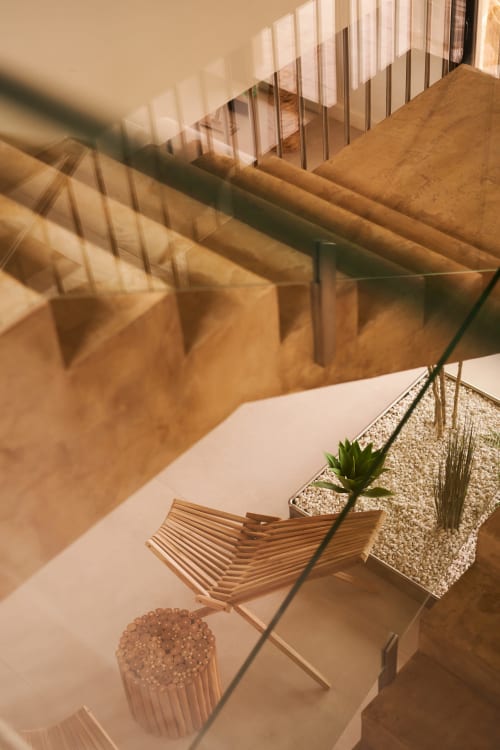Patio minimalista de la villa La Maison D'ambrine con tumbona de madera, plantas en maceta y sombras de toldo rayado junto a la piscina