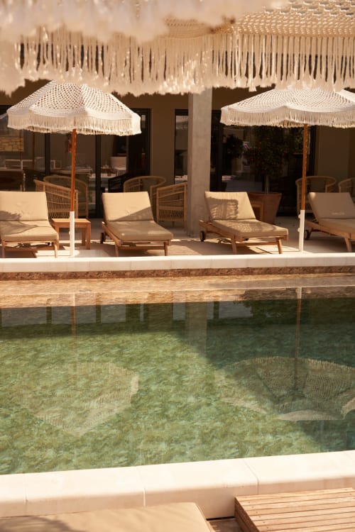 Lujosa terraza junto a la piscina de la villa La Maison D'ambrine en Chamaret con tumbonas, sombrillas crema y agua turquesa