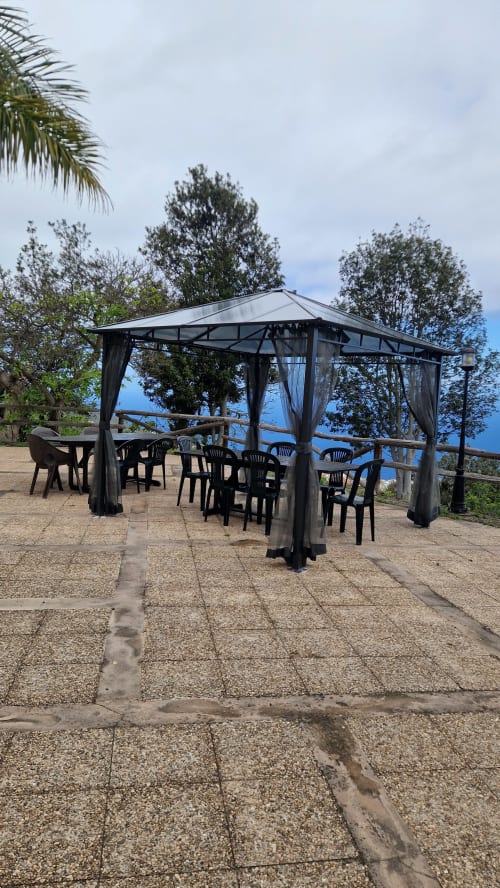 Outdoor gazebo with black chairs and tables at Casonas de marengo in Icod de los Vinos, mountain view terrace with palm trees