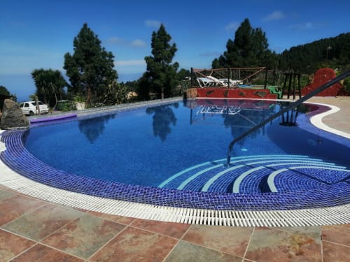 Resort pool with blue mosaic tiles and curved white lounging areas at Casonas de Marengo, Icod de los Vinos, overlooking