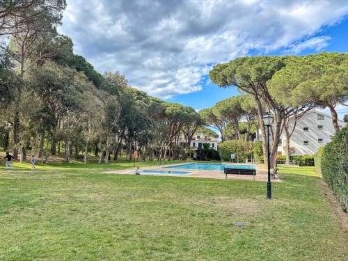 Jardin luxuriant avec piscine à l'hôtel Finques Garcia Enrich à Palafrugell, ombragé par de grands pins