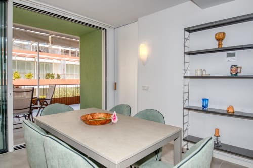 Elegante comedor moderno del hotel Finques Garcia Enrich en Palafrugell con mesa, acentos verdes y vistas al balcón