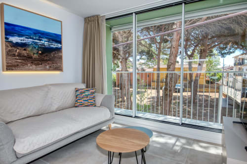 Sala de estar moderna con sofá gris, mesa de madera y ventanales que dan a los árboles en Palafrugell